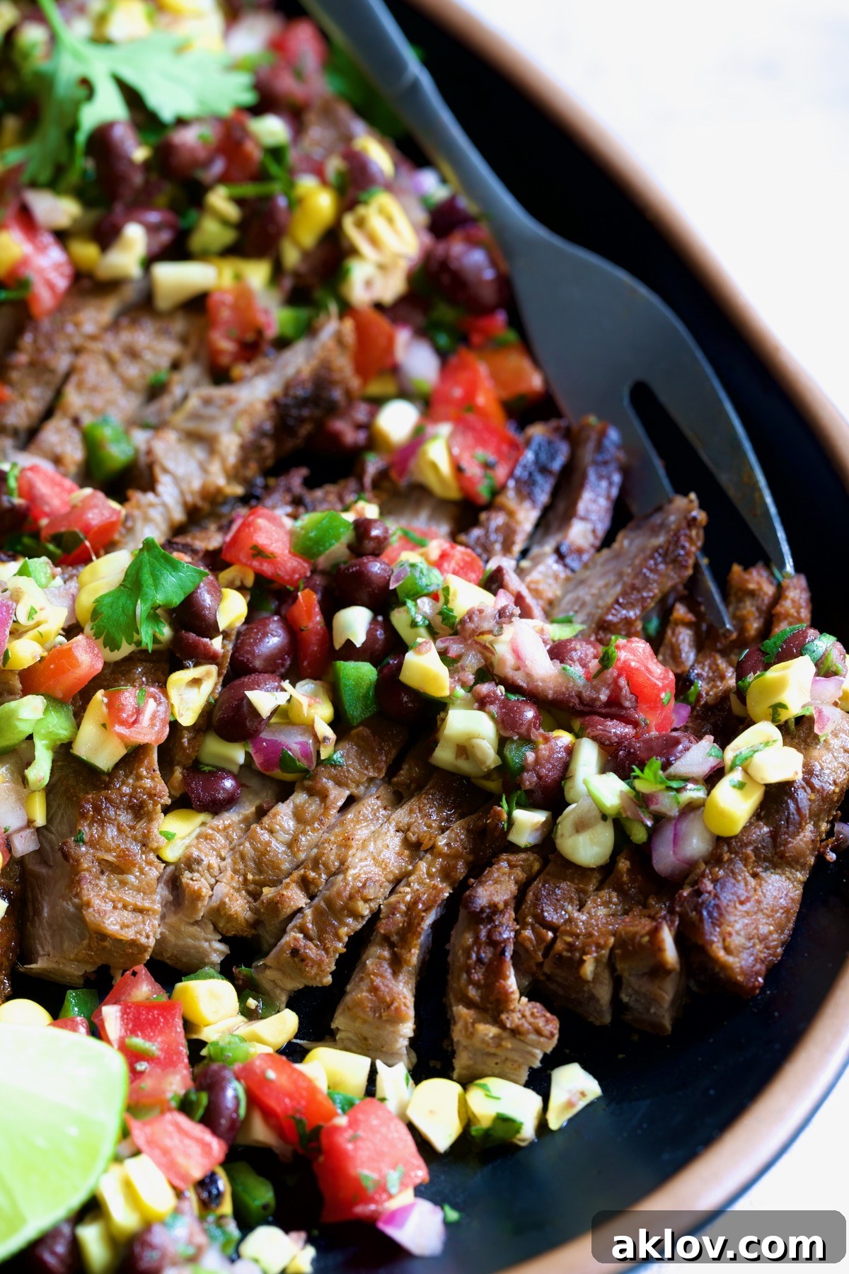 Grilled Skirt Steak with Black Bean Corn Tomato Salad on black platter.