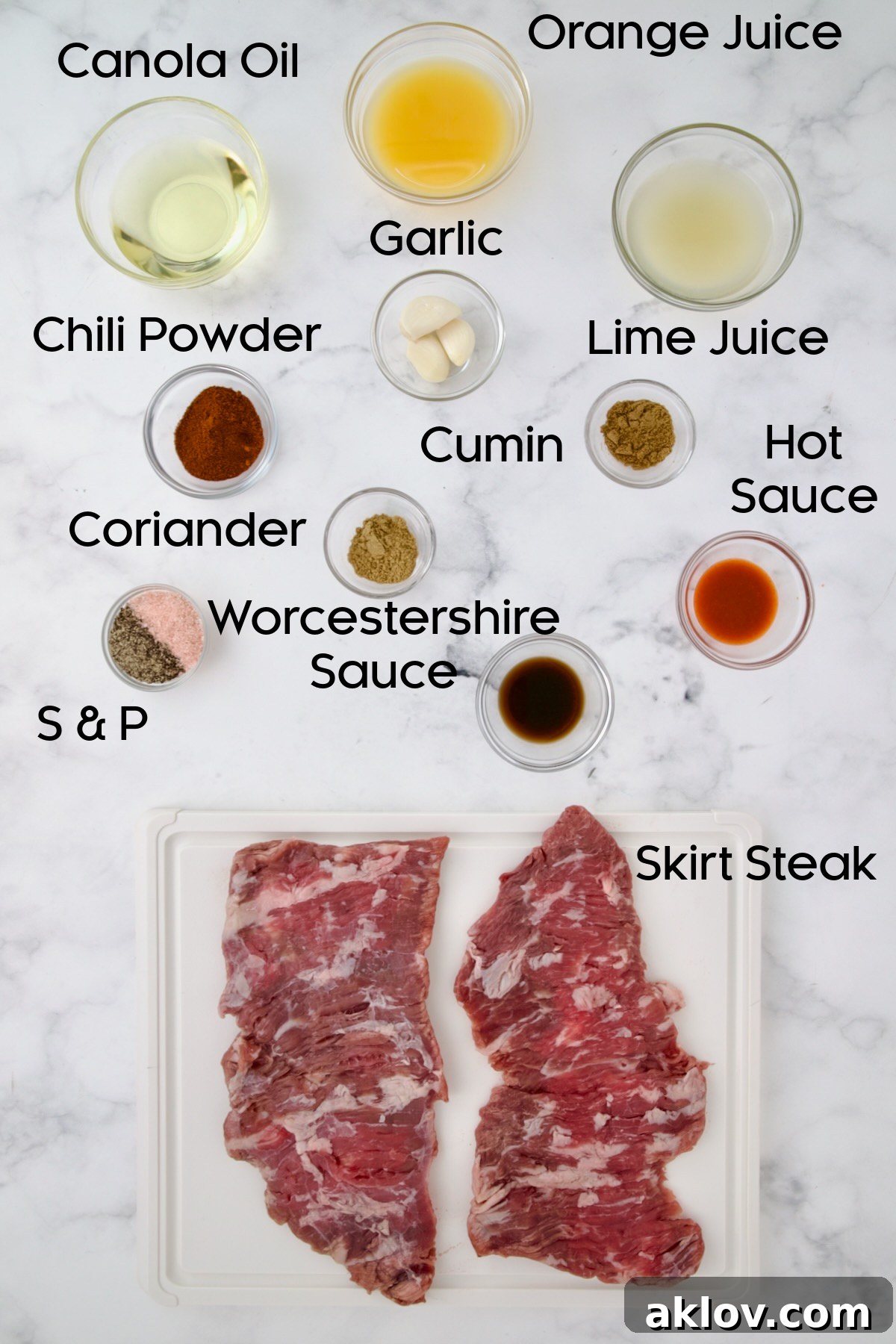 Ingredients for Grilled Skirt Steak in glass bowls with skirt steak on a white plastic cutting board.