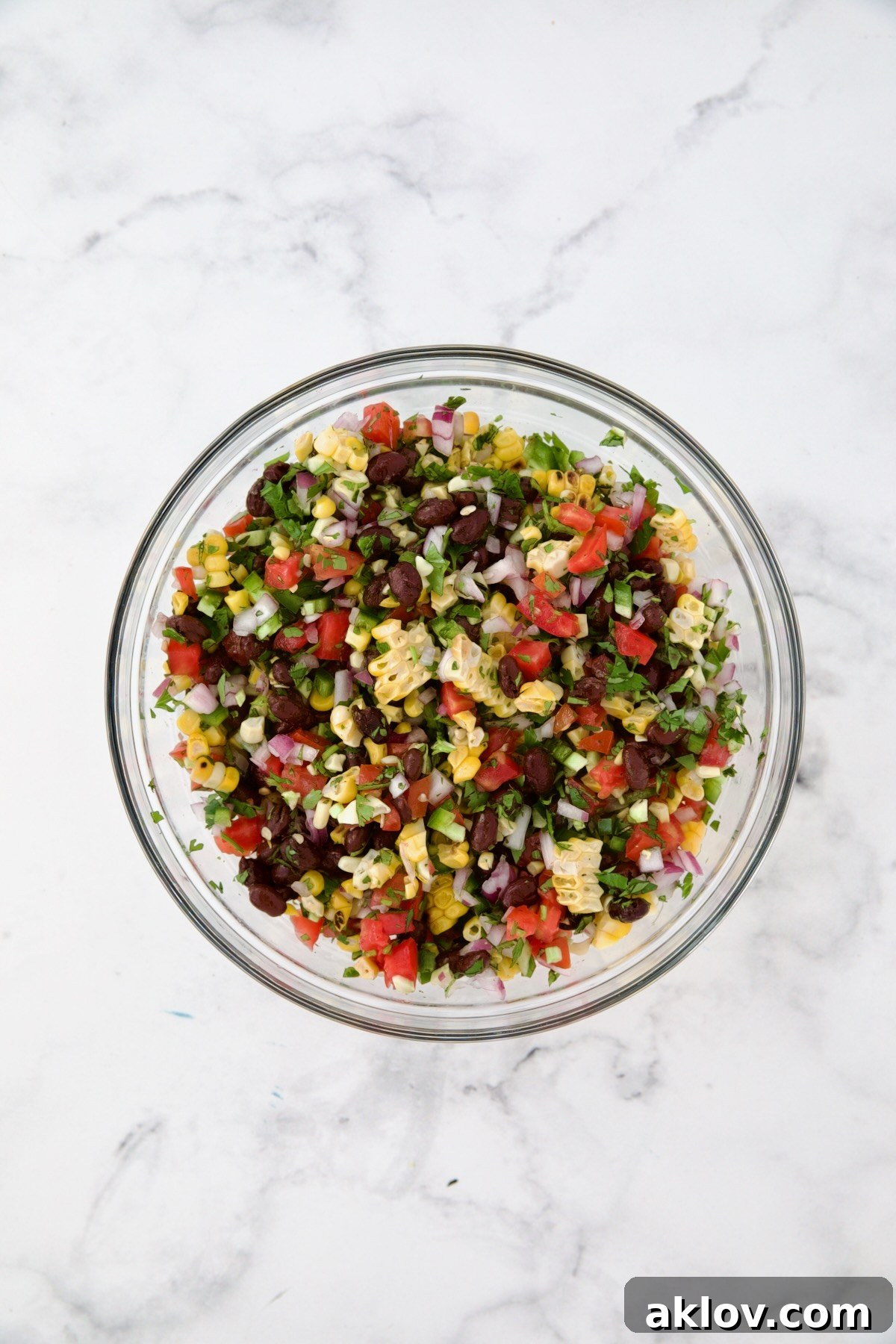 Ingredients for Black Bean Corn Tomato Salad in glass bowl after being combined.