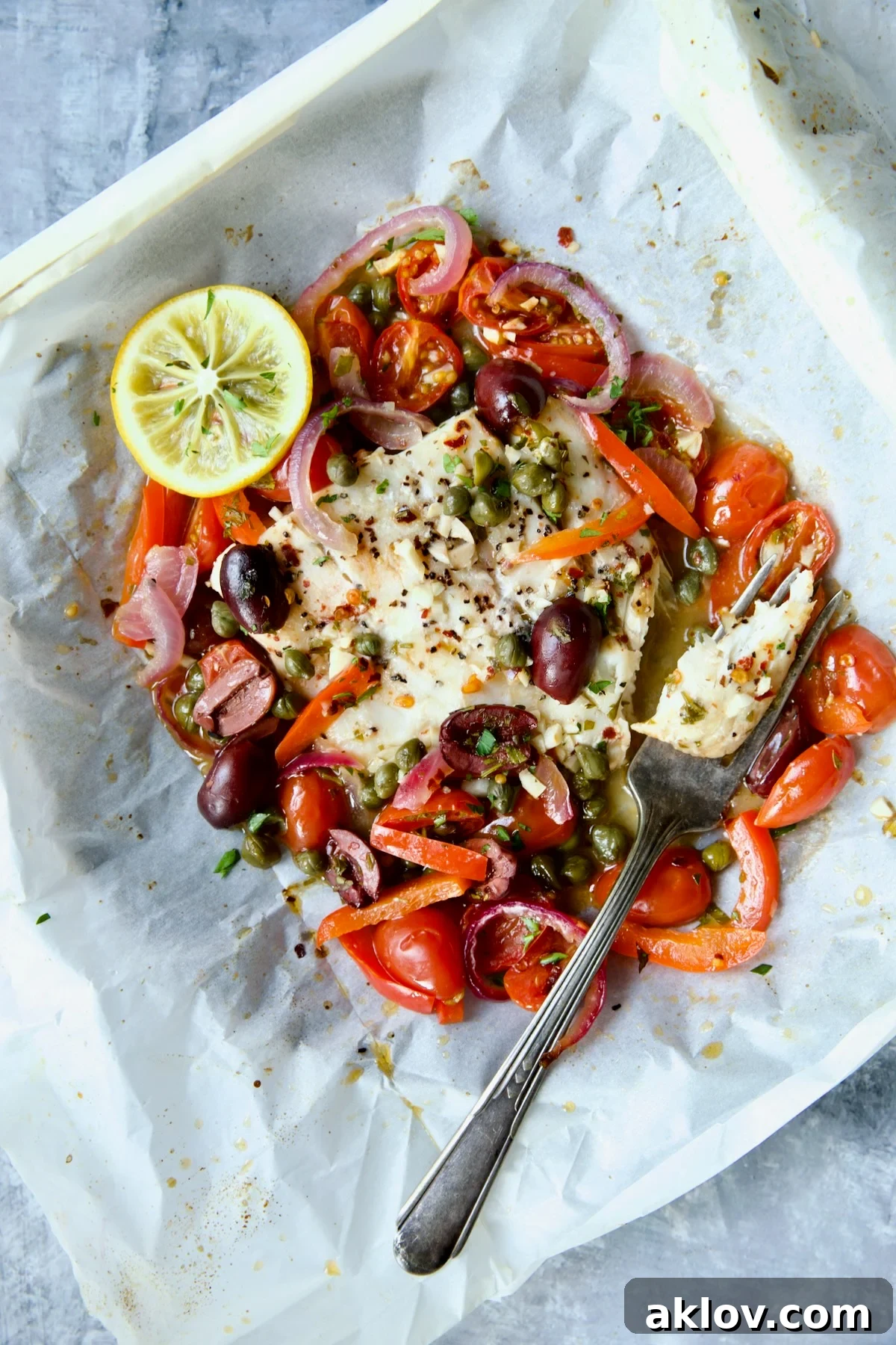 Flavorful Mediterranean Fish Parcels 2 Mediterranean Fish en Papillote opened to reveal baked fish with a piece of the fish on a fork.