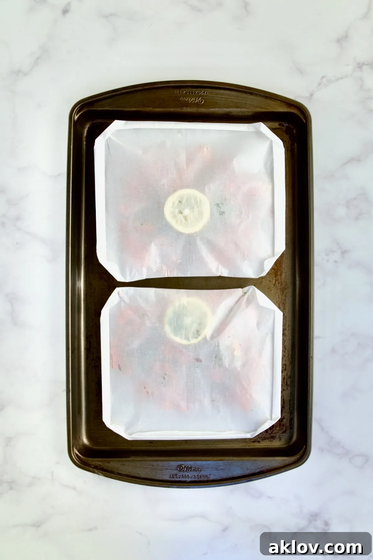 Flavorful Mediterranean Fish Parcels 11 Folded parchment paper packets on rimmed sheet pan ready to be baked.