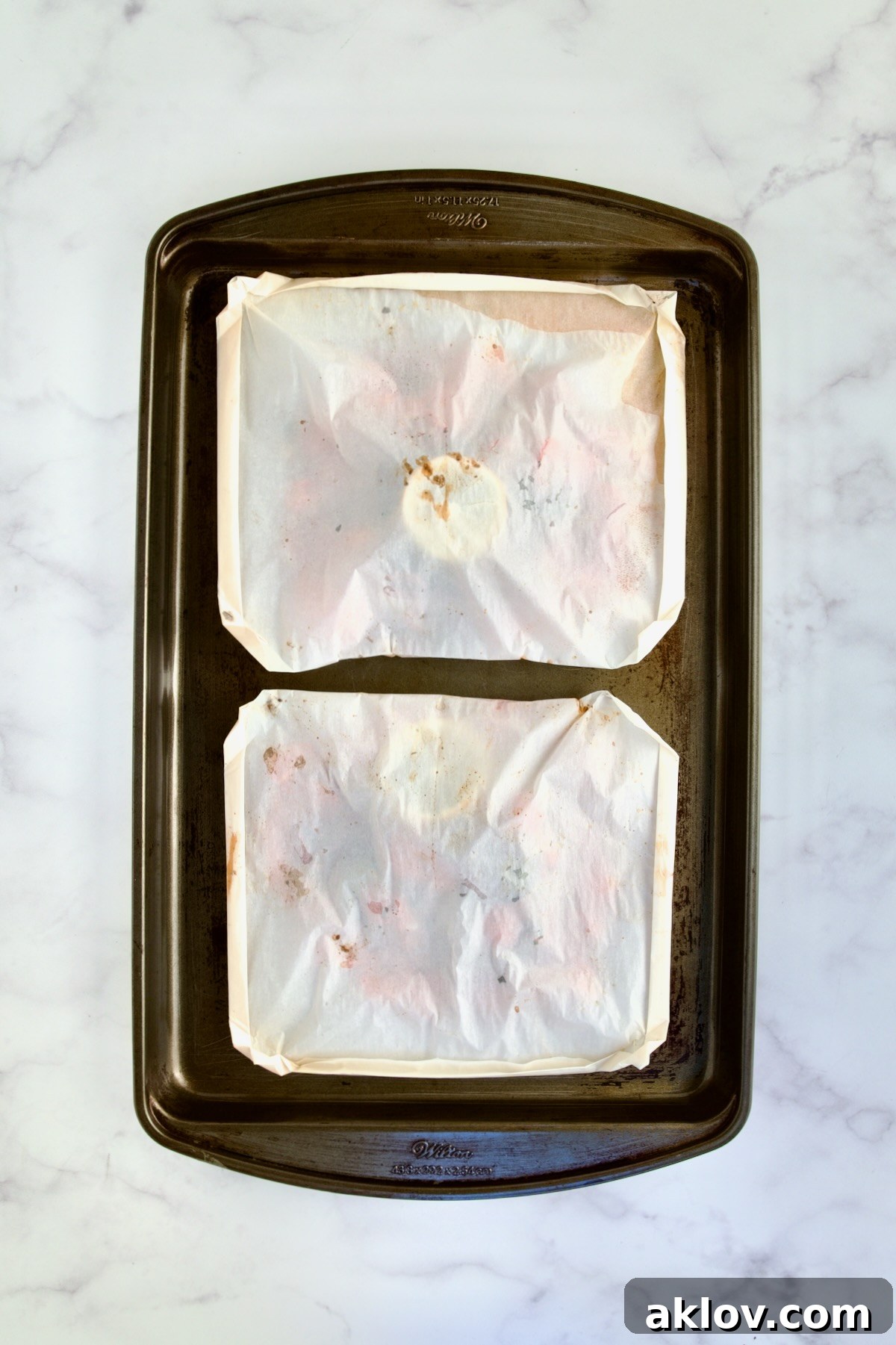 Flavorful Mediterranean Fish Parcels 12 Two baked parchment paper packages on rimmed sheet pan.