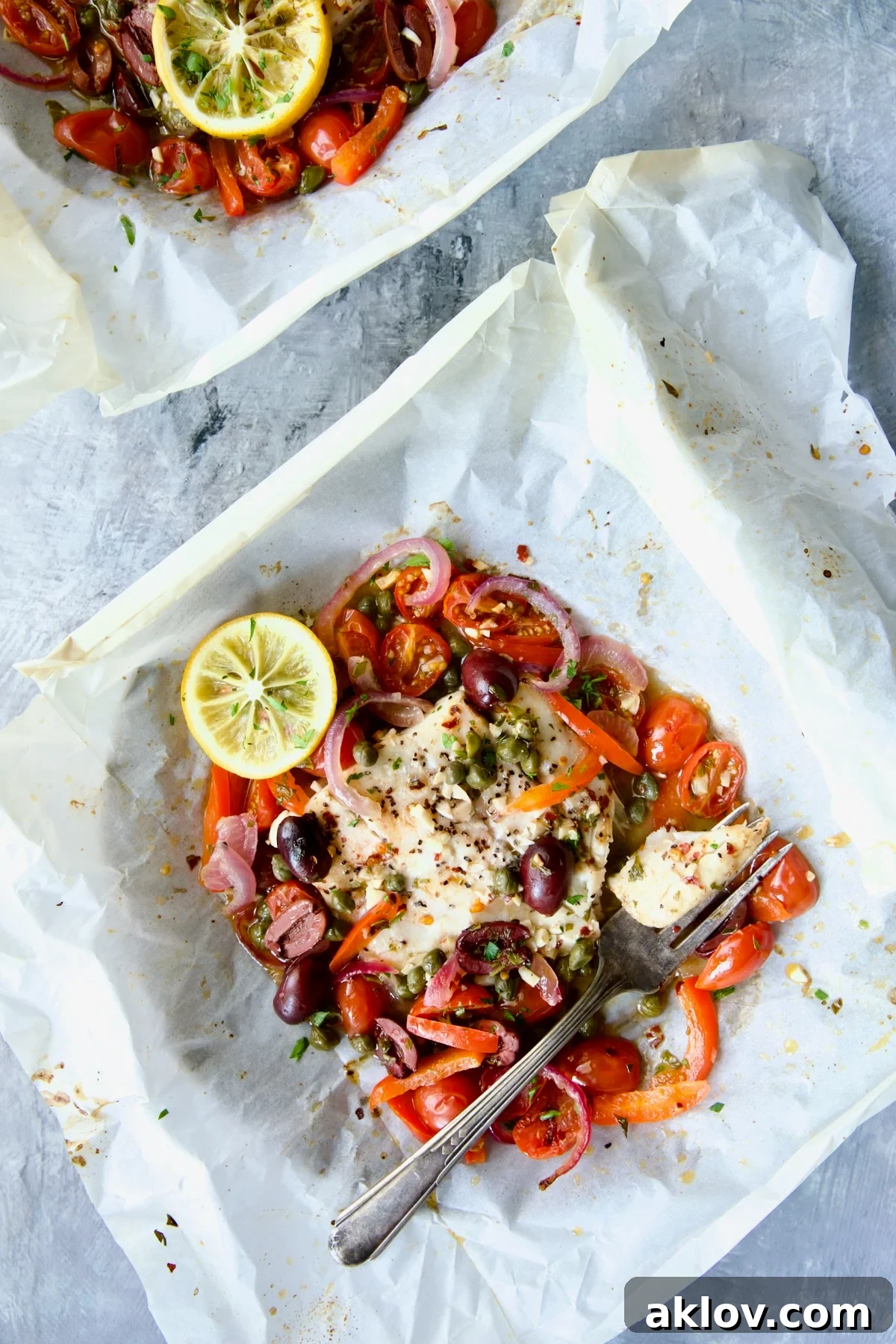 Flavorful Mediterranean Fish Parcels 15 Baked Mediterranean Fish en Papillote on parchment paper with a piece on antique fork.