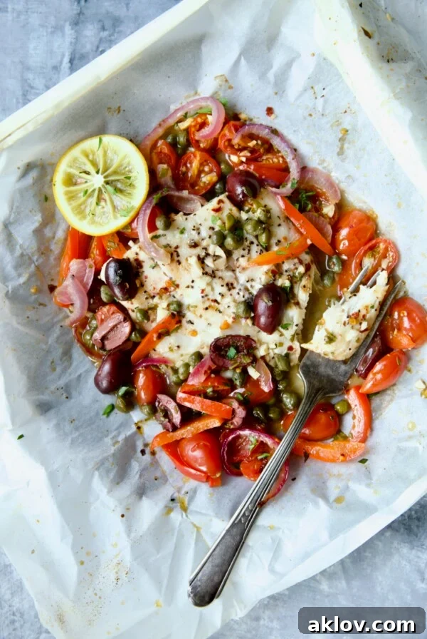 Flavorful Mediterranean Fish Parcels 16 Mediterranean Fish en Papillote opened to reveal baked fish with a piece of the fish on a fork.
