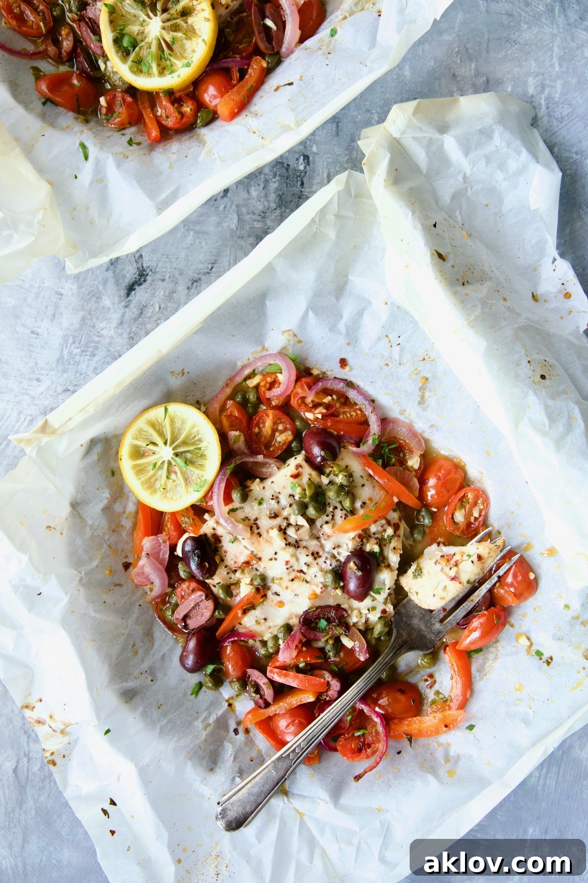 Flavorful Mediterranean Fish Parcels 3 Baked Mediterranean Fish en Papillote on parchment paper with a piece on antique fork.