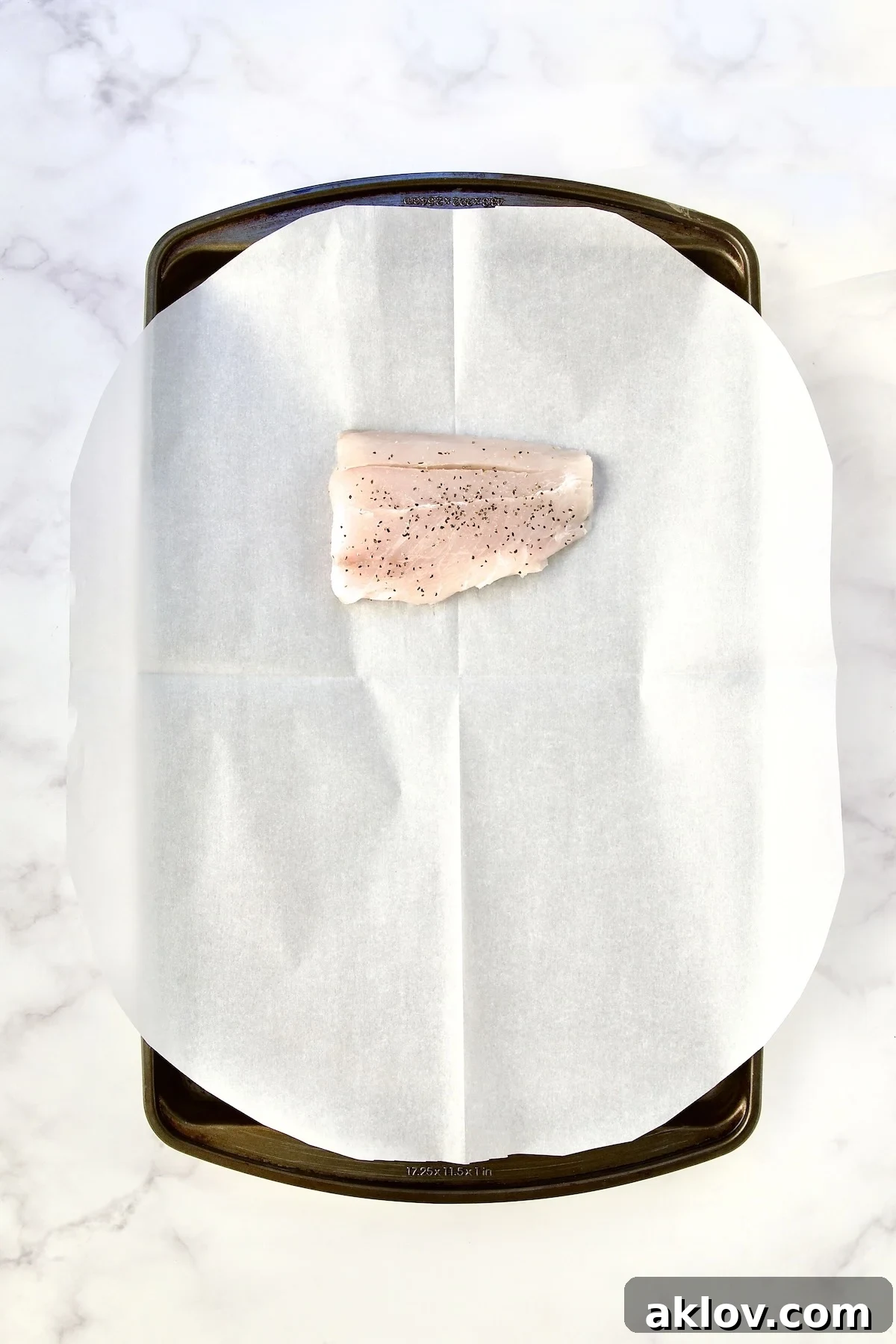 Flavorful Mediterranean Fish Parcels 8 Piece of fish on parchment paper on rimmed sheet pan.