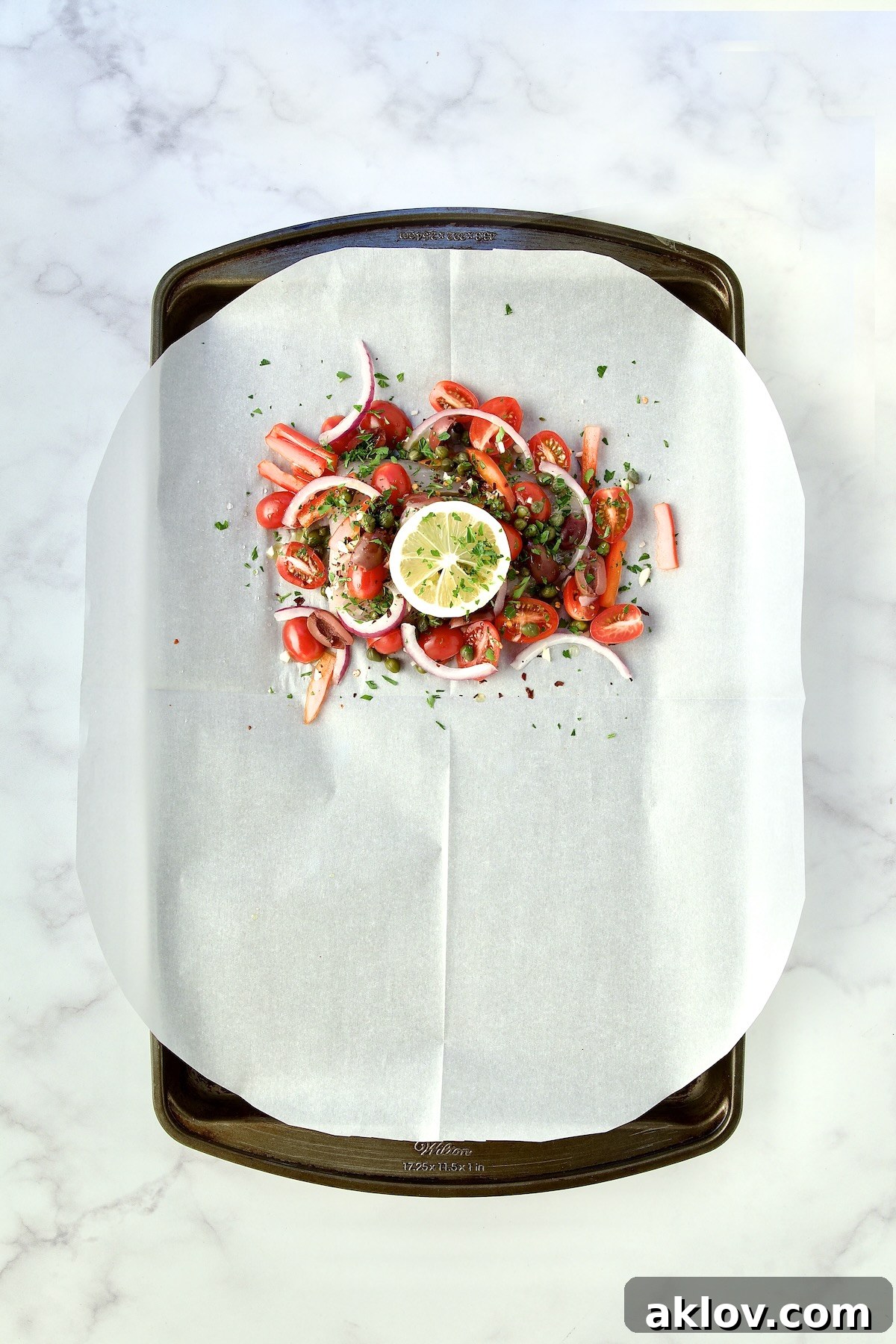 Flavorful Mediterranean Fish Parcels 10 Assembled fish and other ingredients on parchment paper on rimmed sheet pan.