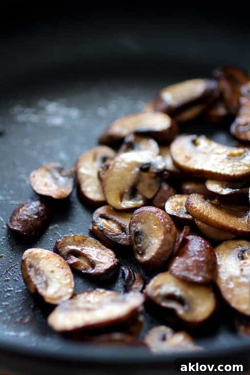 Photo of baby Portobello mushrooms (cremini) being sauteed in a nonstick skillet.