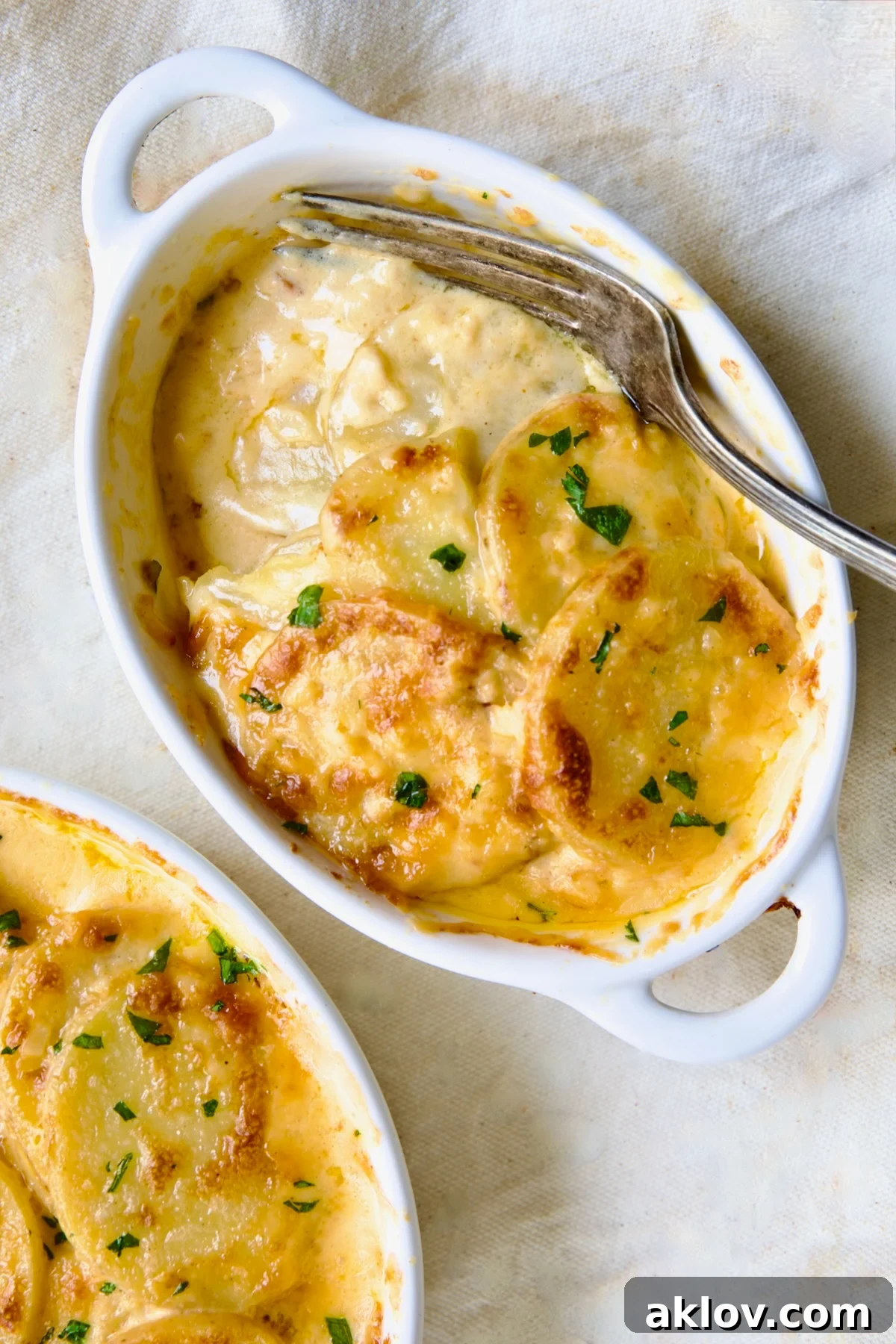 A single dish of Au Gratin Potatoes for Two, close-up with a fork digging in to reveal creamy layers, inviting a taste.