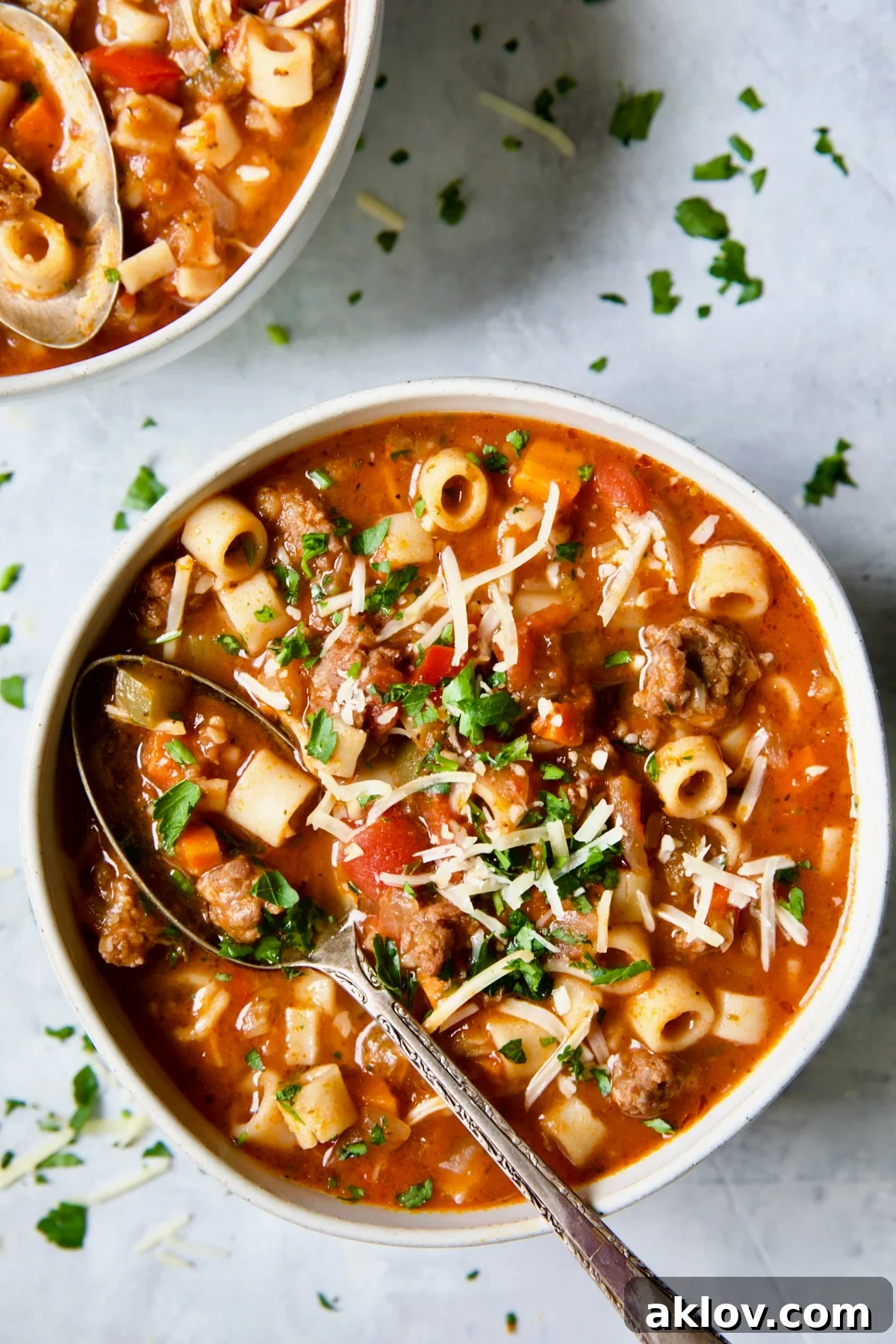 Close-up of a bowl of Italian Sausage Soup with a spoon scooping out pasta and vegetables.