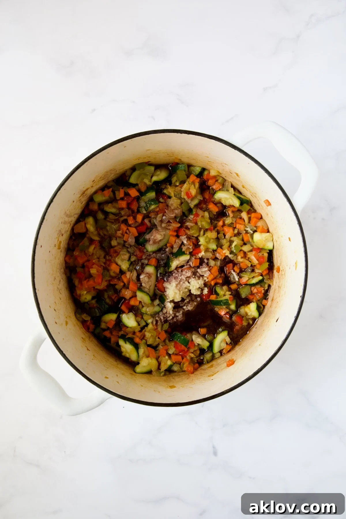 Red wine and minced garlic added to the sautéed vegetables in a white Dutch oven.