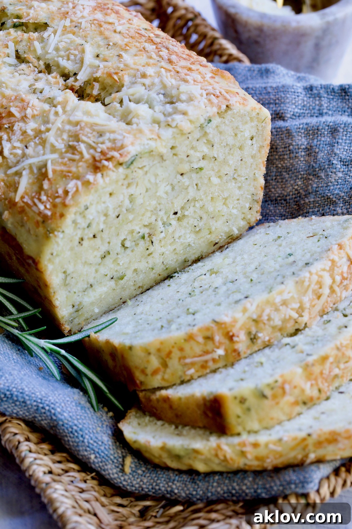 Sliced loaf of Easy Herb Bread on blue napkin in wicker basket.