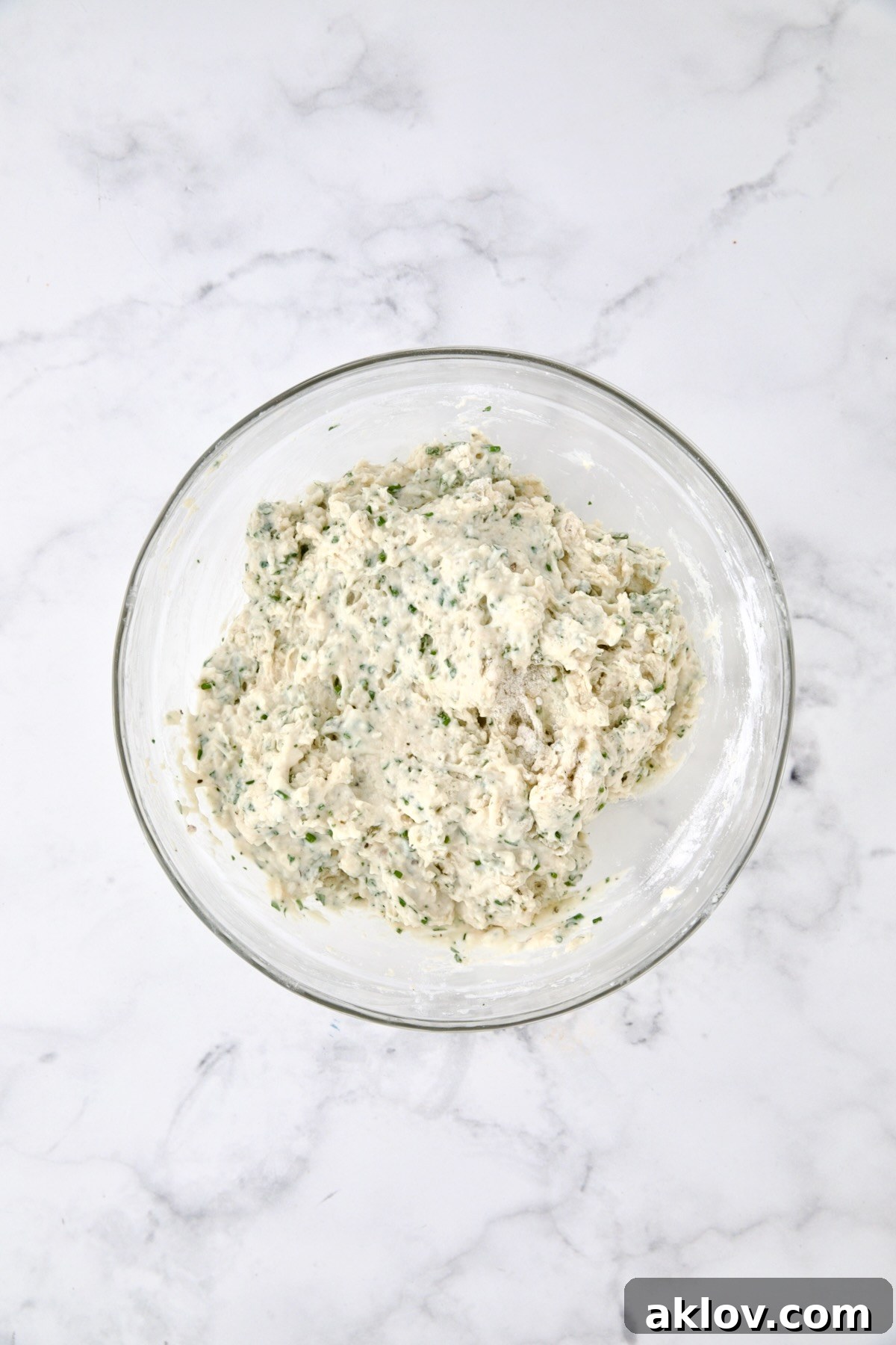 Wet and dry ingredients for bread combined in glass bowl.