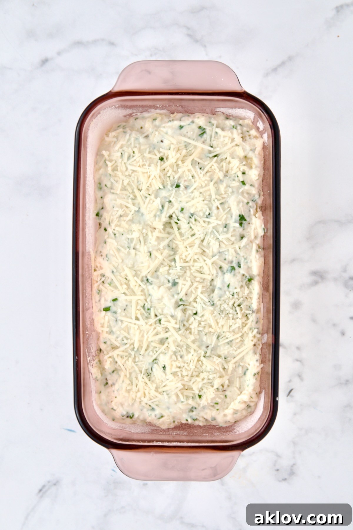 Unbaked herb bread in glass baking dish.