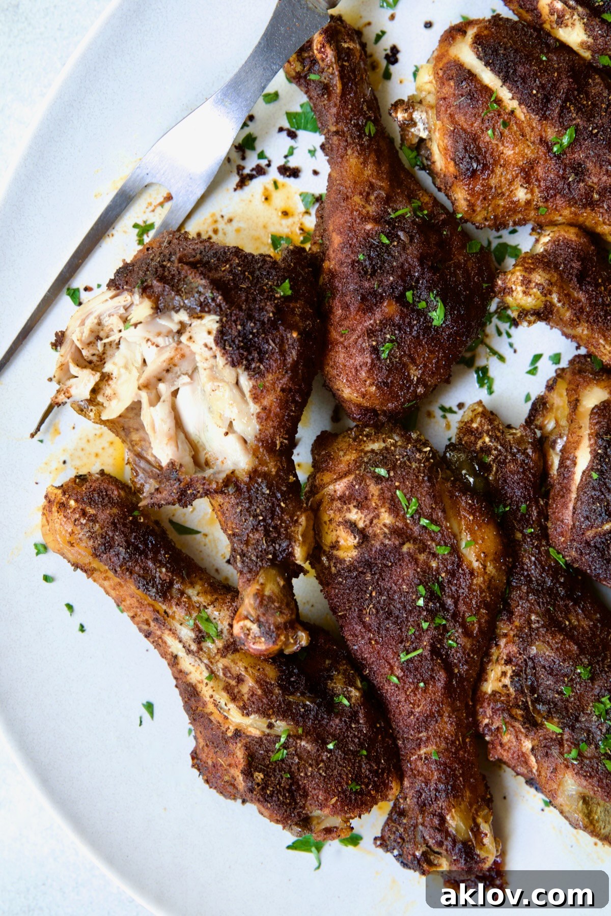 Baked Cajun Chicken Drumsticks on an oval white platter with one drumstick slightly pulled apart.