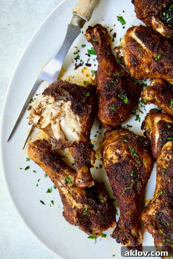 Baked Cajun Chicken Drumsticks on oval white platter, showing juicy interior.