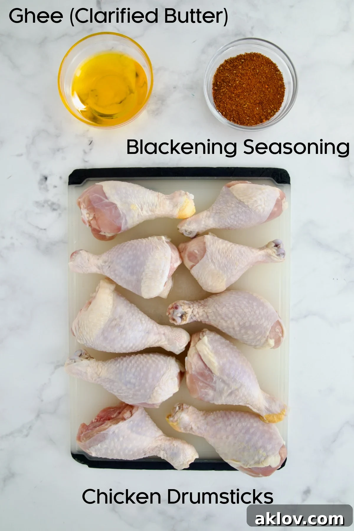 Ten uncooked chicken drumsticks, a bowl of melted clarified butter, and a bowl of blackening seasoning displayed.