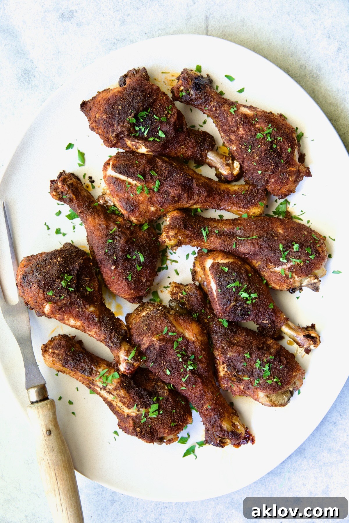 Ten beautifully presented Baked Cajun Chicken Drumsticks on a white oval platter, ready to be served.