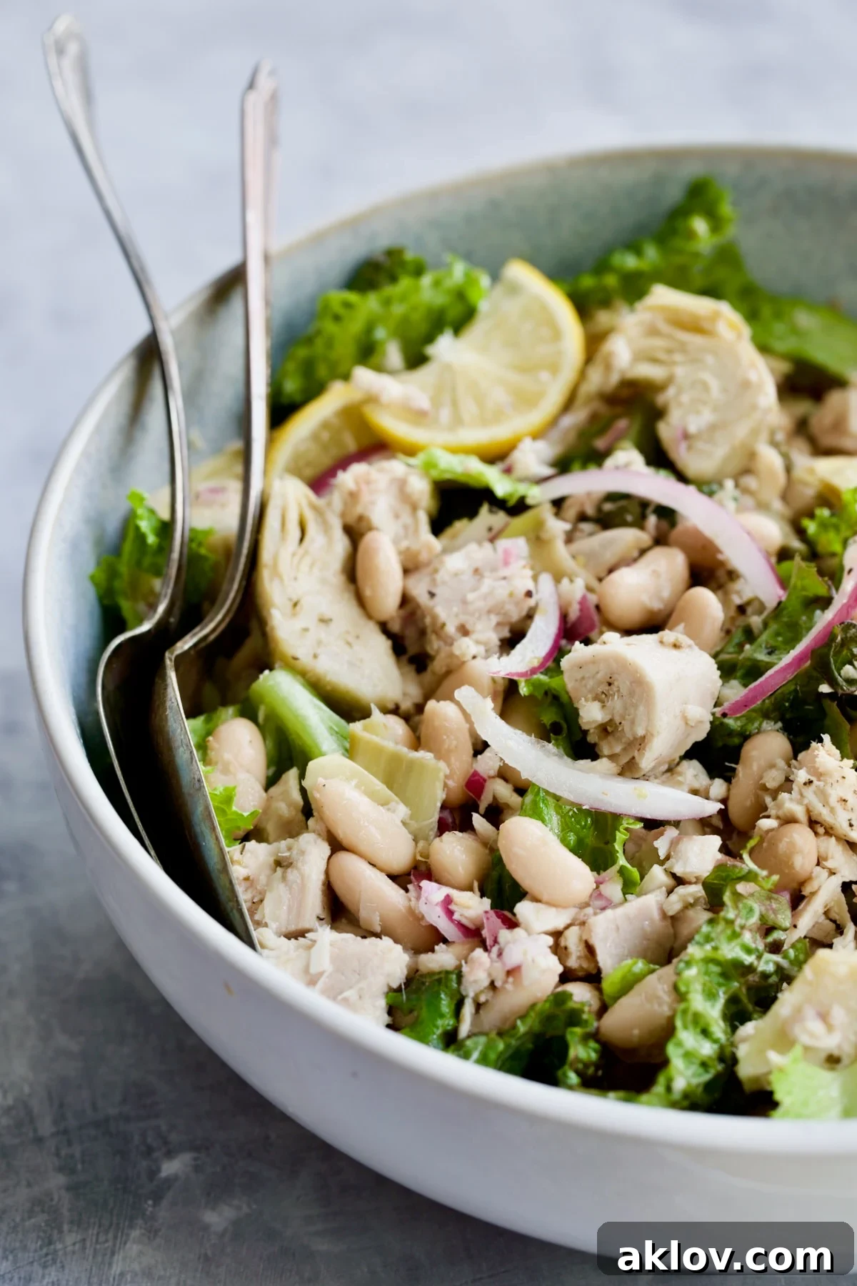 Salad in serving bowl with serving utensils.