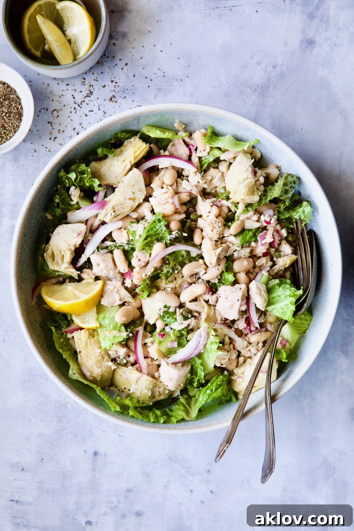 Tuna, White Bean and Artichoke Salad in serving bowl with serving utensils.