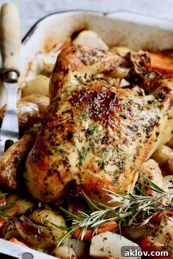 Photo of Garlic Herb Butter Roast Chicken with Root Vegetables with meat fork nearby.
