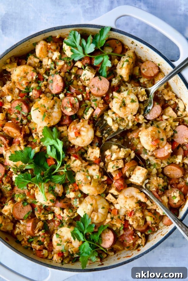 Low-Carb Jambalaya with Chicken Shrimp and Sausage with serving utensils garnished with fresh parsley.