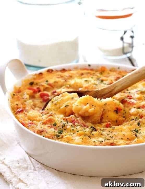 Spicy Shrimp and Grits Casserole with Gouda Cheese in a round white baking dish with a wooden spoon scooping some out.