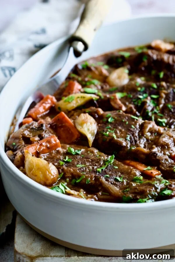 Short Ribs Bourguignon in white oval serving dish with meat fork.