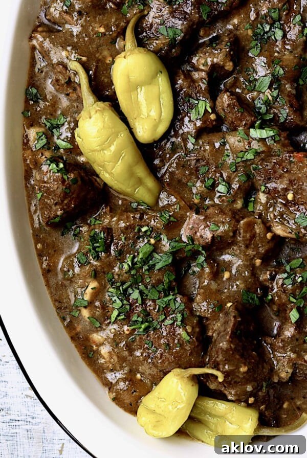 Mississippi-Style Boneless Short Ribs Without Packaged Mixes - Overhead close-up shot on white platter. Tender boneless short ribs slow-cooked in a tangy, savory sauce, a healthier take on the classic Mississippi Pot Roast.