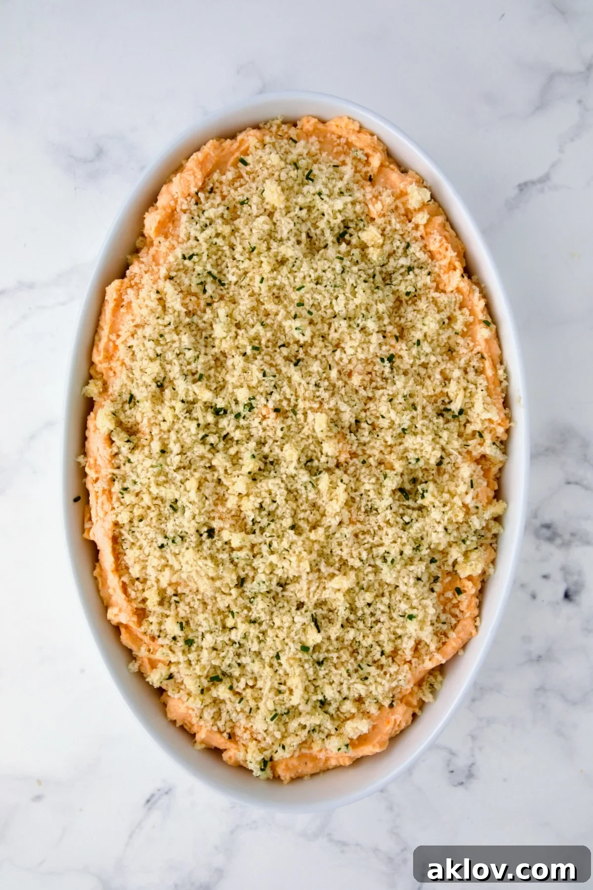 Potato and Sweet Potato Bake in white oval baking dish before being baked.