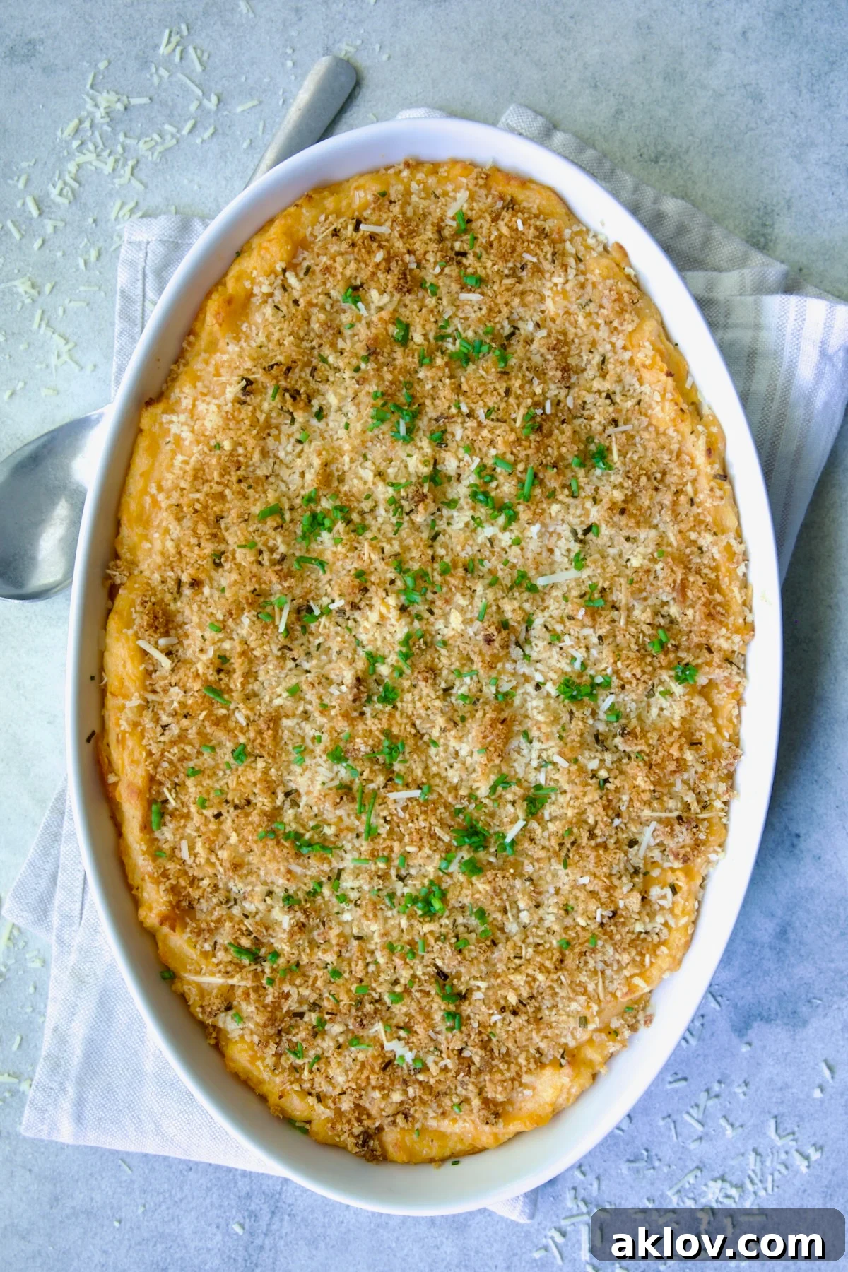 Potato and Sweet Potato Bake in white oval baking dish with silver serving spoon.