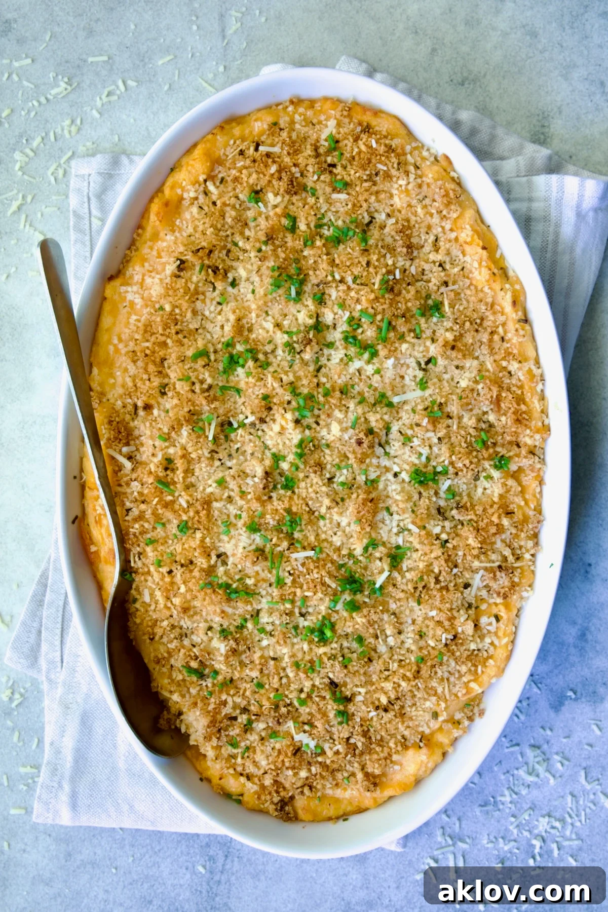 Potato and Sweet Potato Bake in white oval baking dish with silver serving spoon.