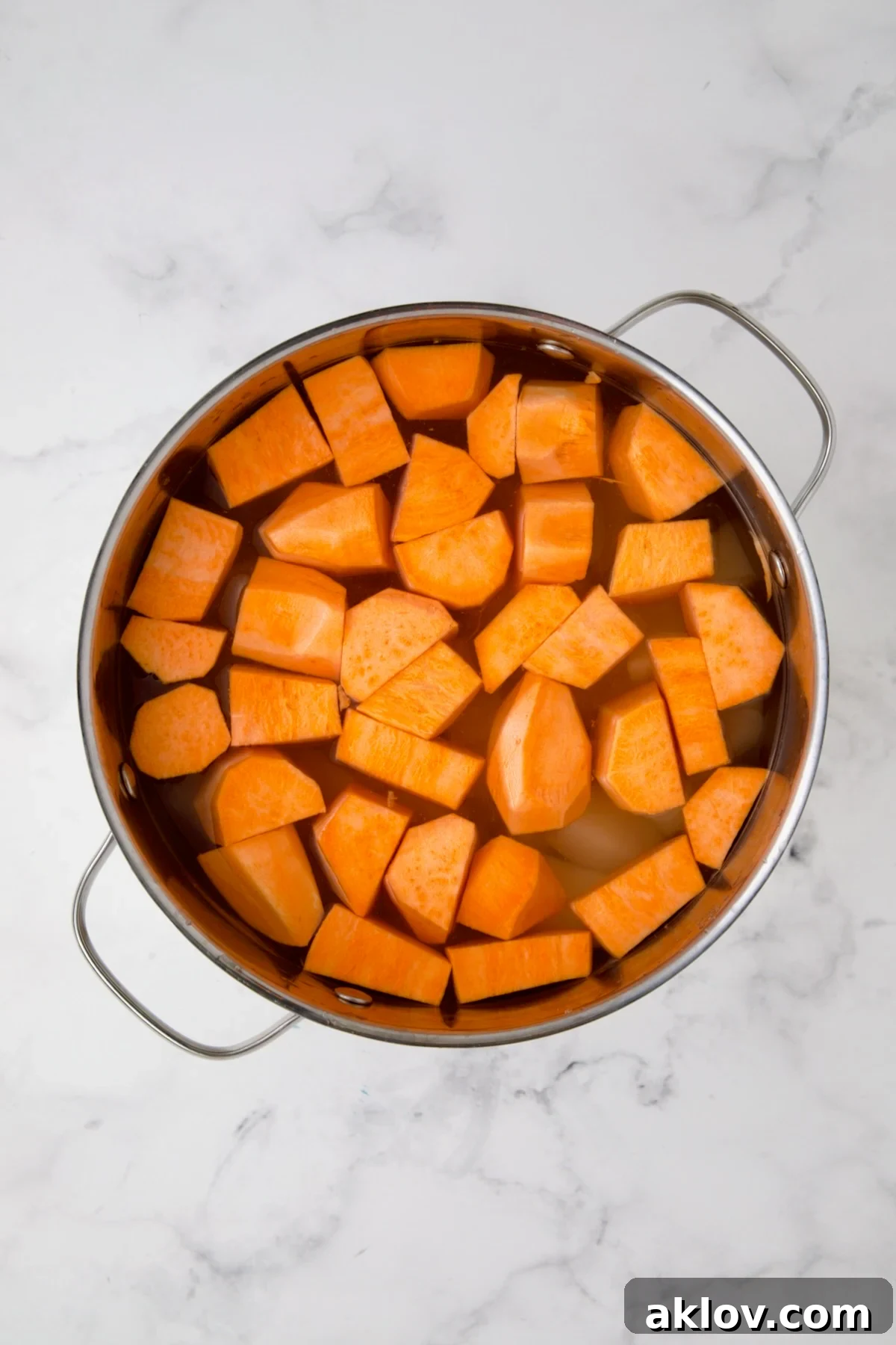 Russets and sweet potatoes in water in stainless steel pot before being cooked.