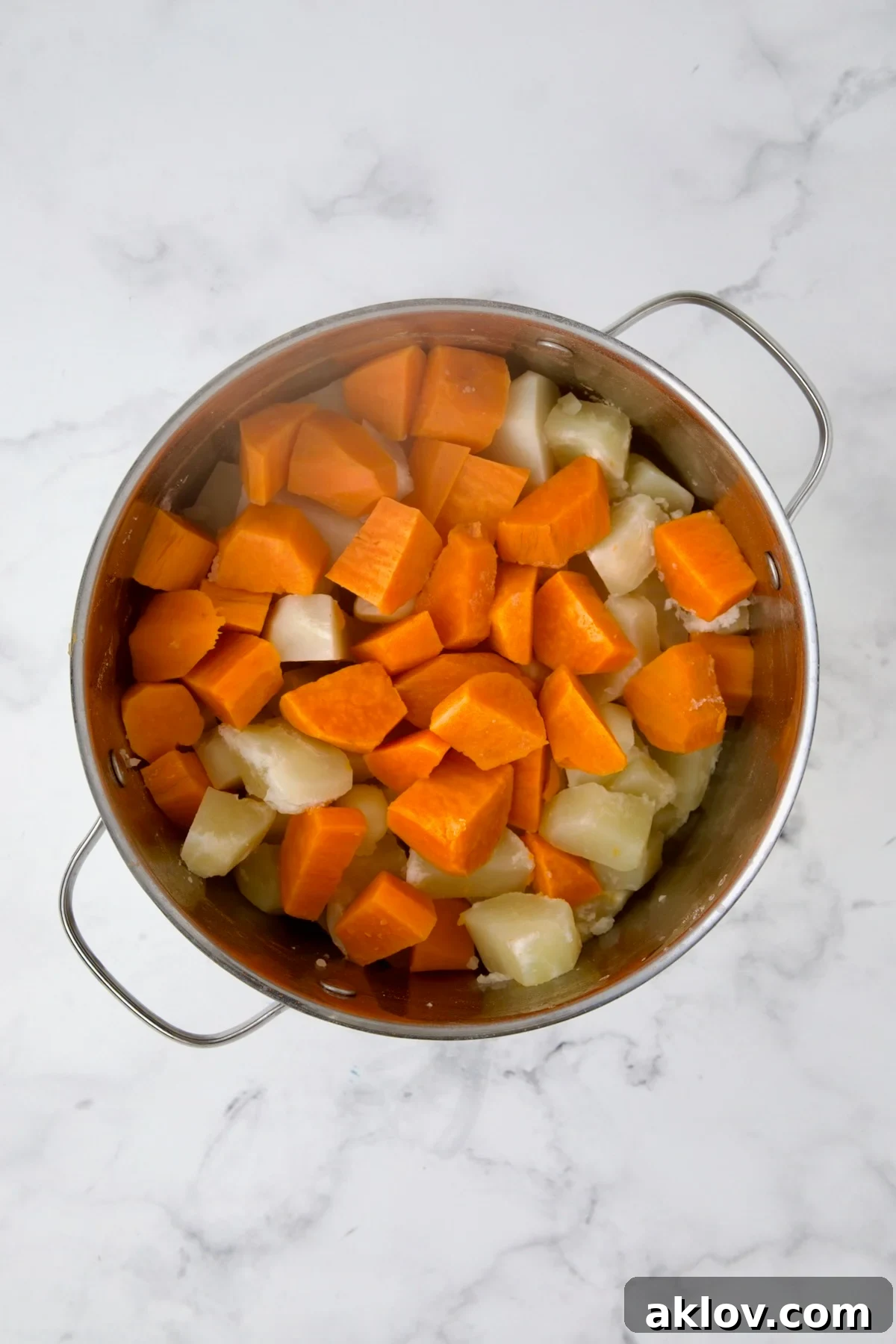Drained Russets and sweet potatoes in stainless steel pot after being cooked.