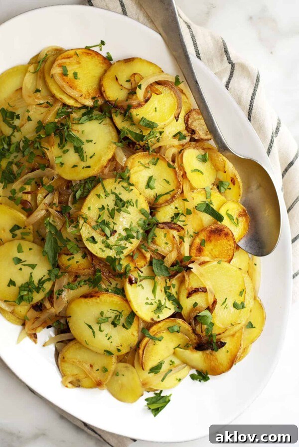 Lyonnaise Potatoes on oval white platter, showcasing beautifully caramelized onions and golden potatoes.
