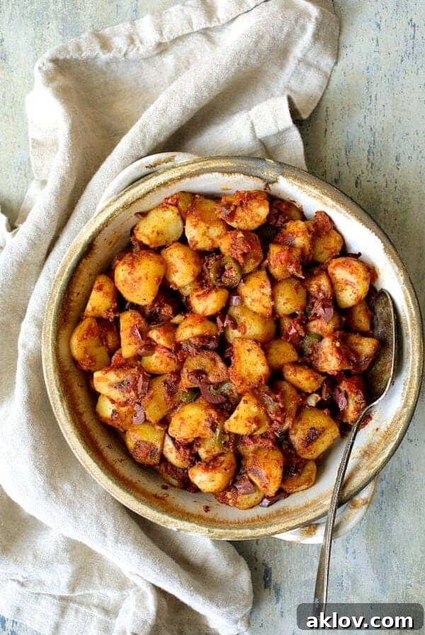 Chile Potatoes (Patatas Bravas Chilenas) in earthenware bowl with serving spoon, vibrant with a spicy tomato dressing.