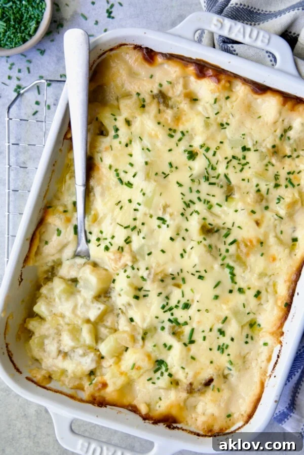 Hatch Green Chile au Gratin Potatoes in white rectangular baking dish with serving spoon scooping some out, showcasing a unique Southwestern twist.