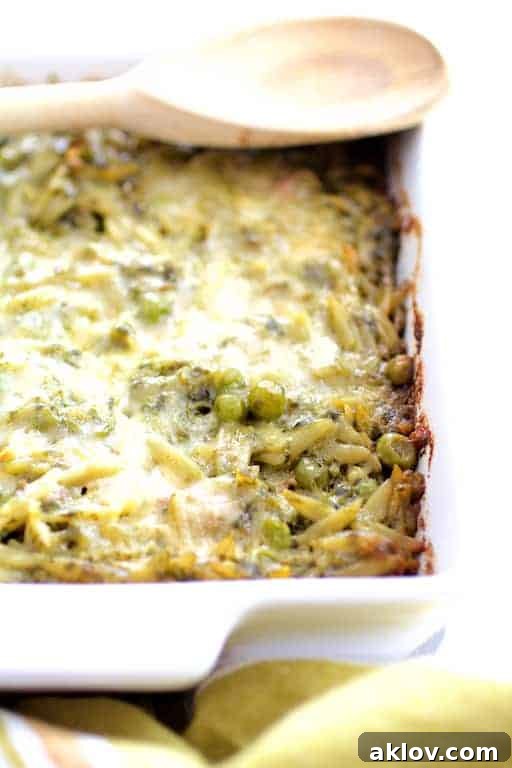Photo of Baked Orzo with Pesto Peas Prosciutto and Mascarpone in white baking dish before being served.