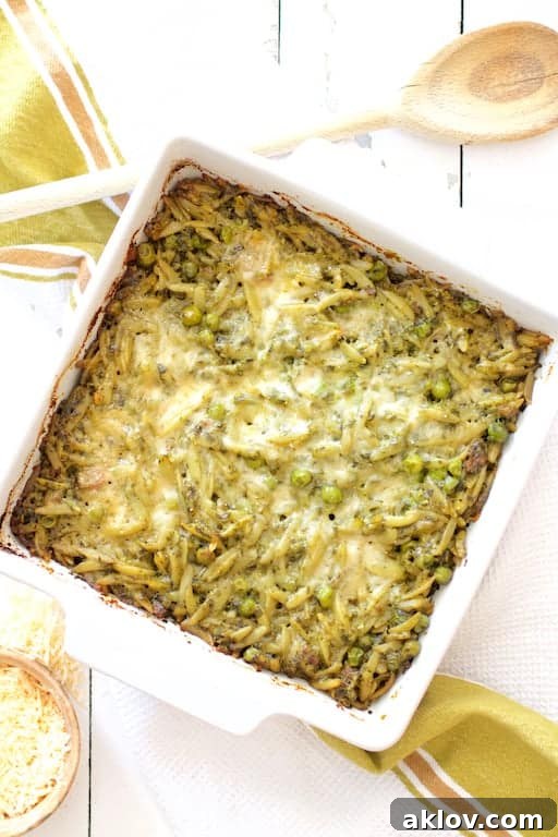 Photo of Baked Orzo with Pesto Peas Prosciutto and Mascarpone on white wooden background.