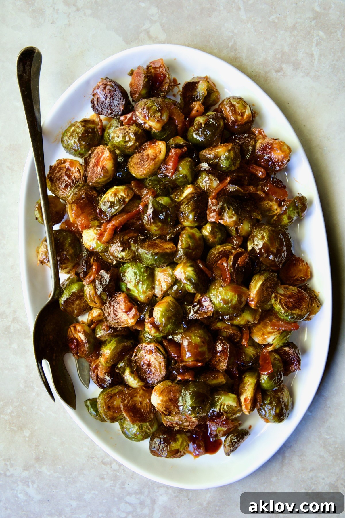 Maple Bacon Gochujang Brussels Sprouts on white platter with serving fork.