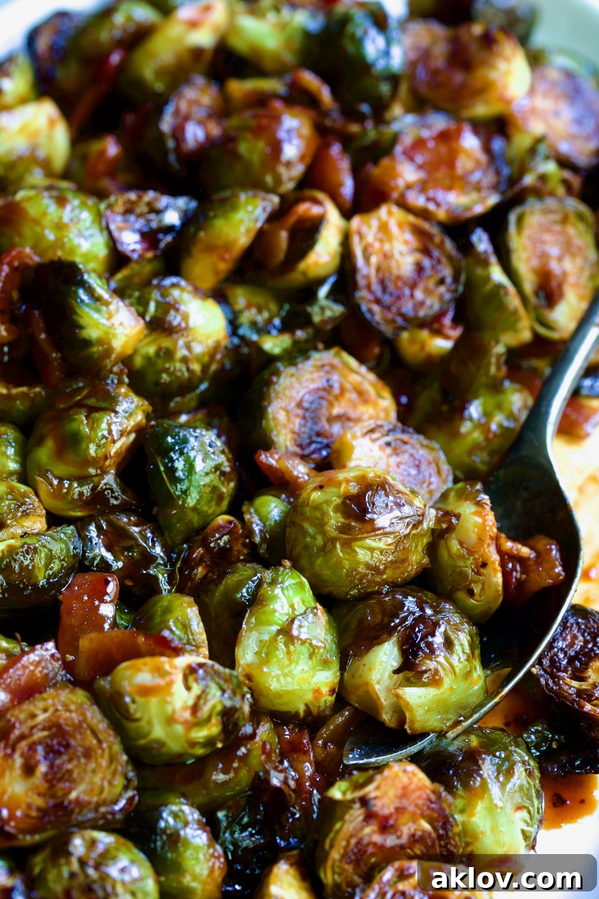 Maple Bacon Gochujang Brussels Sprouts on white platter with serving fork.