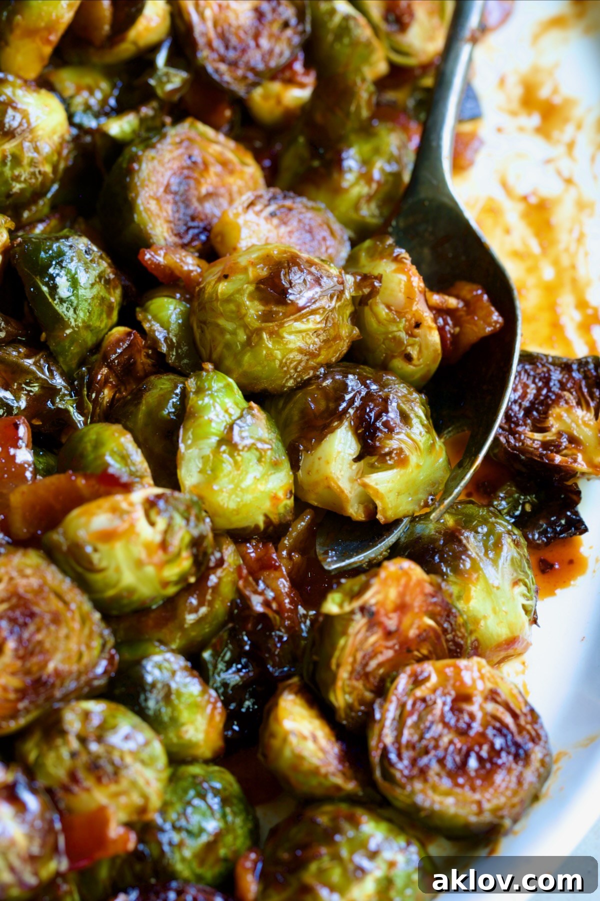 Maple Bacon Gochujang Brussels Sprouts on white platter with serving fork.