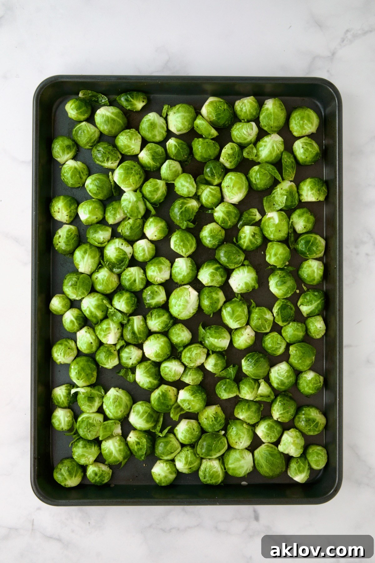 Halved Brussels sprouts on rimmed sheet pan.