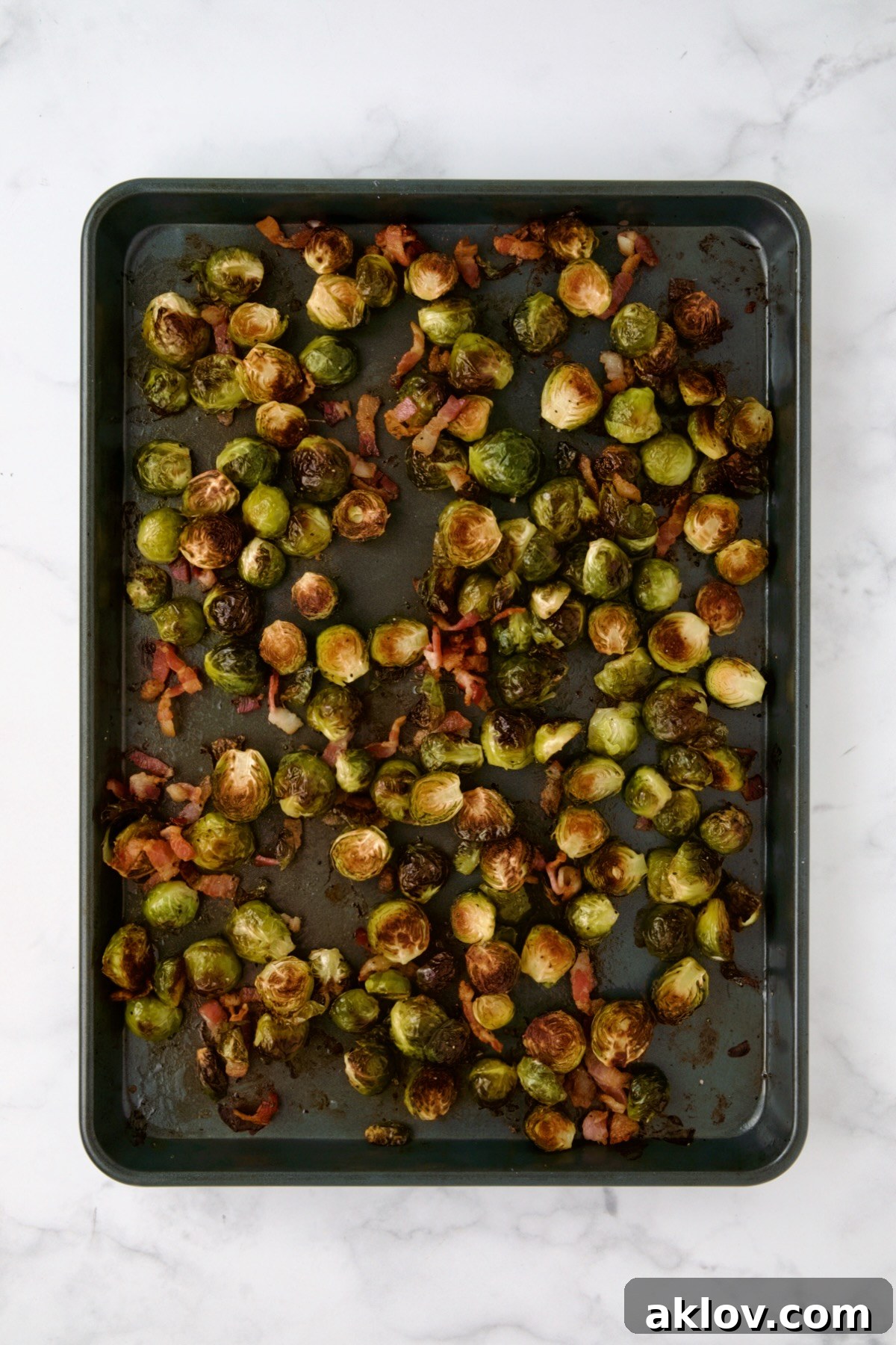 Roasted Brussels sprouts and bacon on rimmed sheet pan.