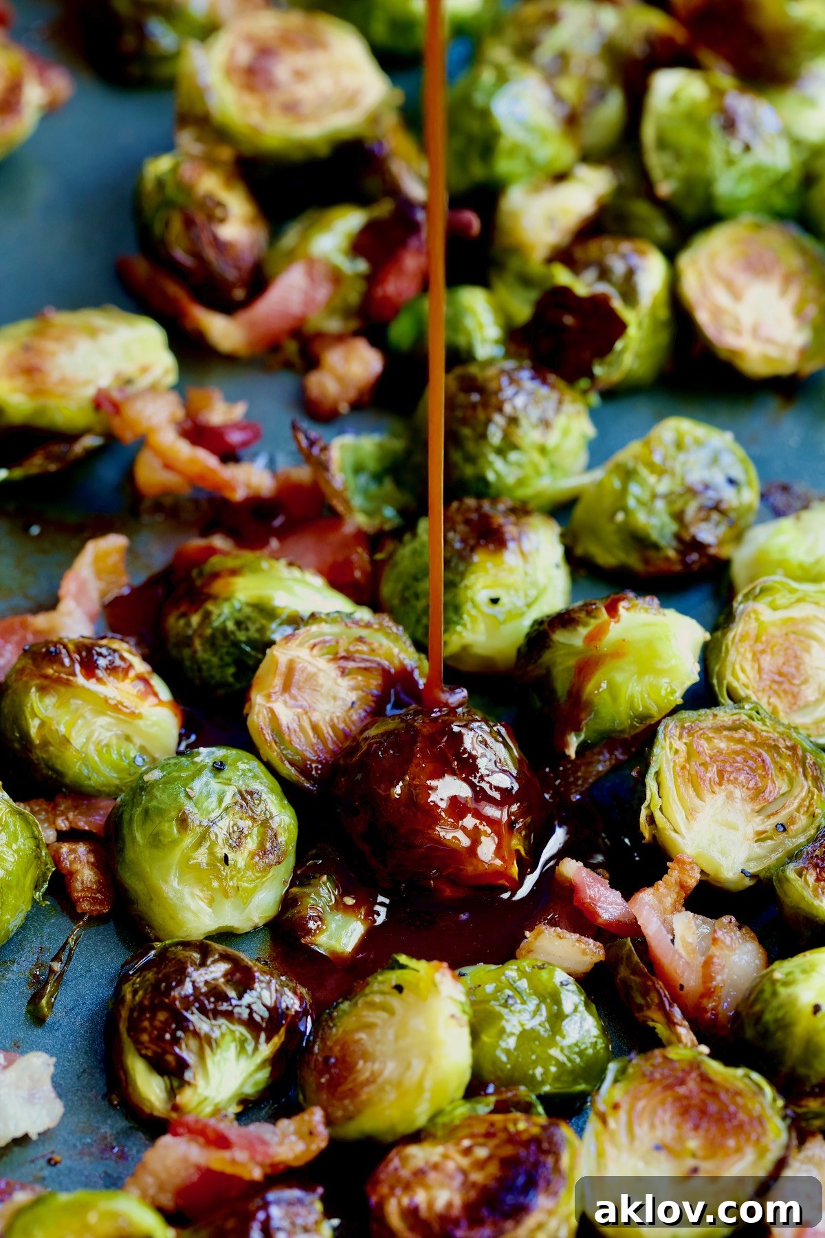 Glaze being poured onto Brussels sprouts on sheet pan.