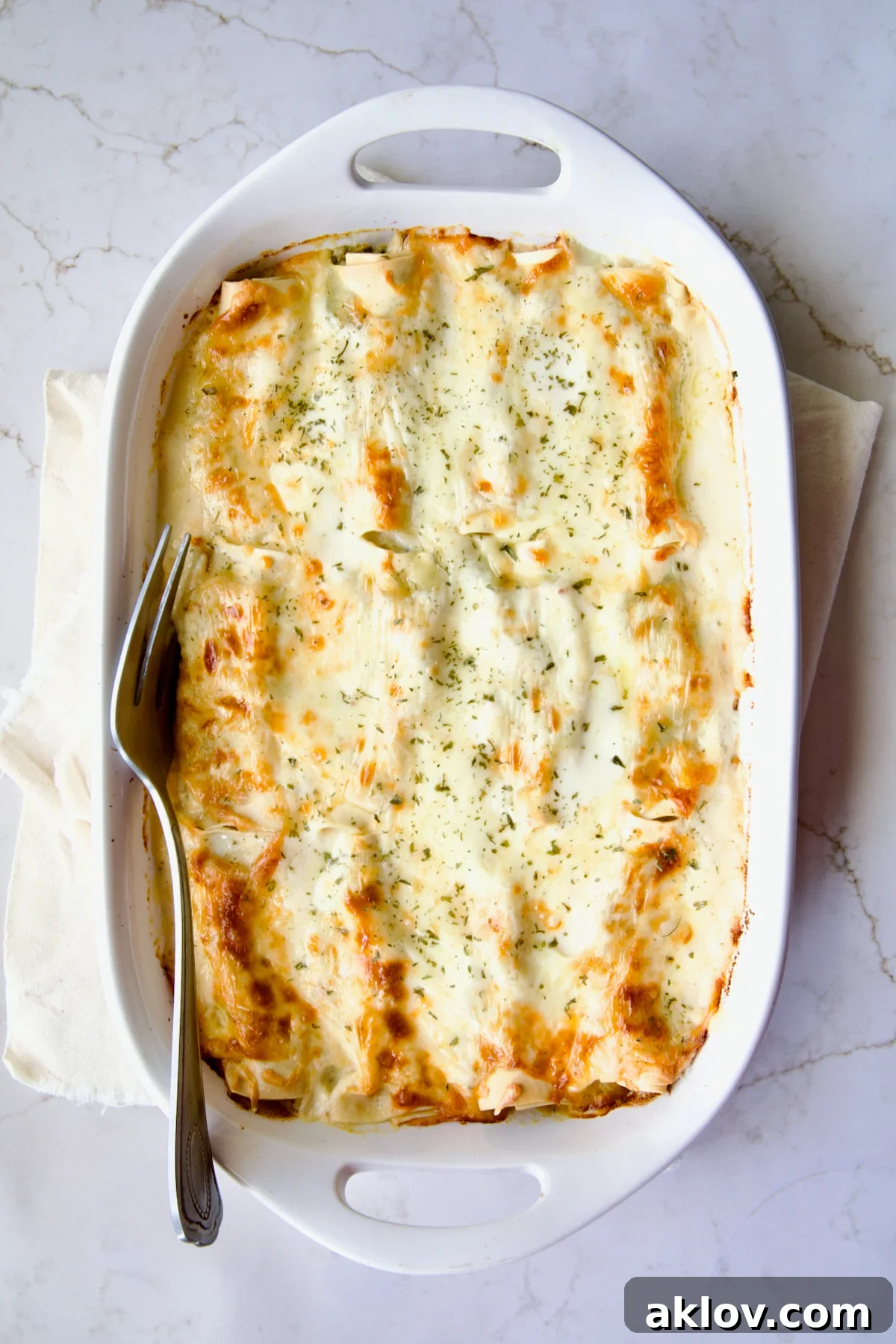 Cannelloni with Chicken, Spinach and Artichokes in white baking dish with serving fork.