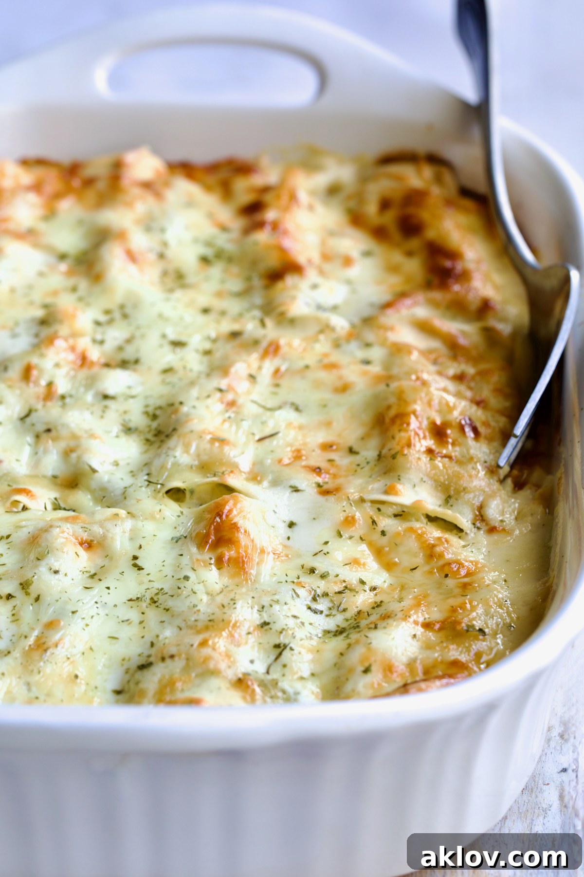 Cannelloni with Chicken, Spinach and Artichokes in white baking dish with serving fork.