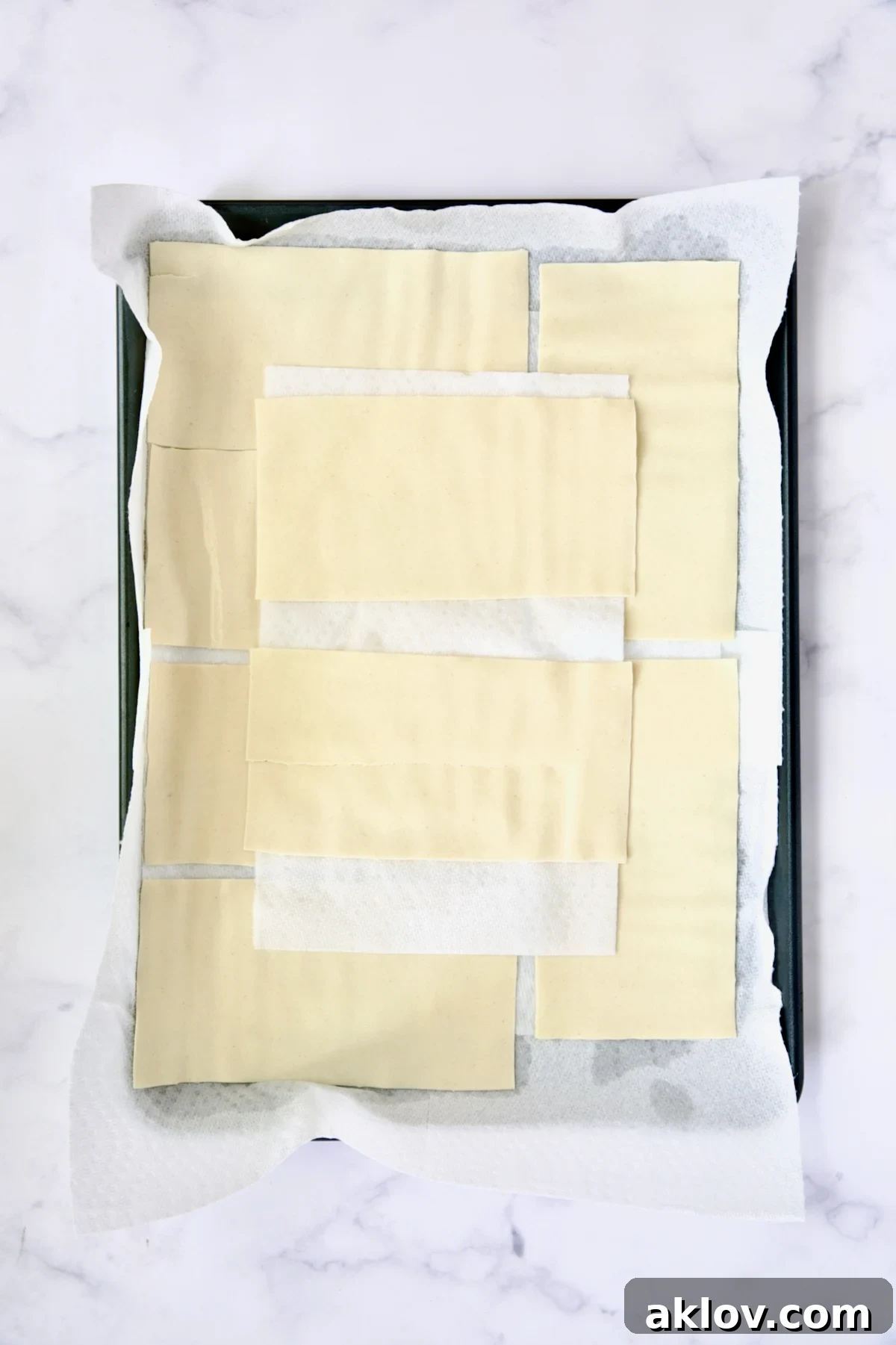 12 flat lasagna sheets on paper towels on rimmed sheet pan.