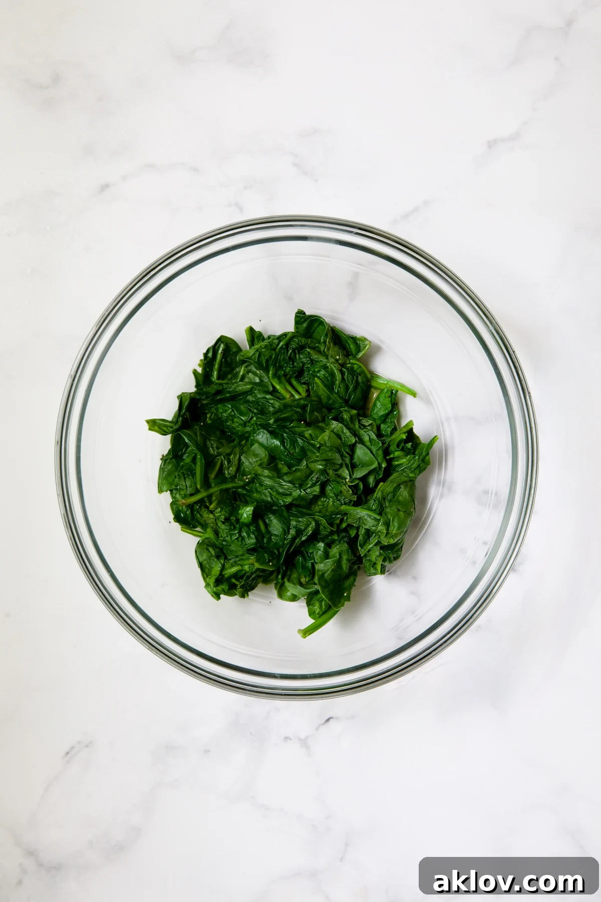 Cooked spinach in glass bowl.