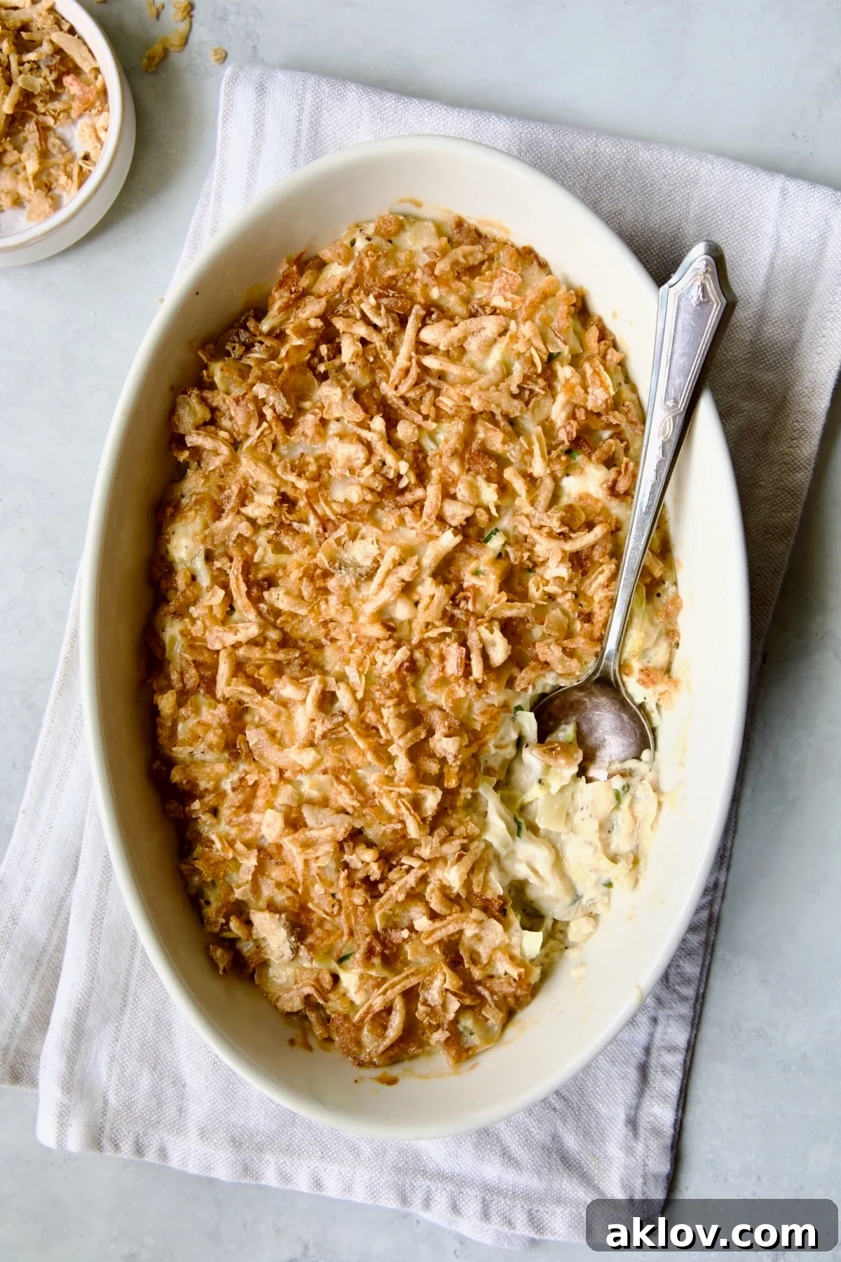 A beautifully presented Creamed Cabbage Casserole in an elegant white oval baking dish, with an ornate serving spoon resting beside it, ready to be enjoyed.